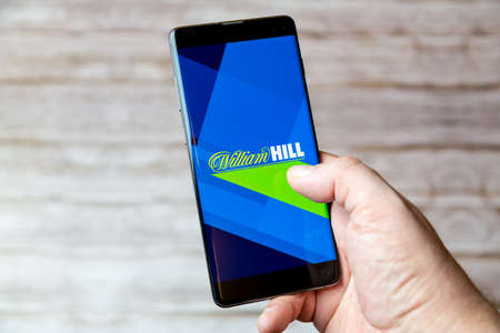 02-04-2021 Portsmouth, Hampshire, UK A handing holding a Mobile phone or cell phone with the William Hill betting app on screenのeditorial素材
