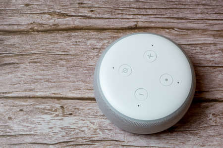 02-04-2021 Portsmouth, Hampshire, UK An Amazon Echo dot or amazon Alexa device isolated on a wooden table or deskのeditorial素材