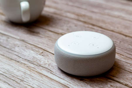 02-04-2021 Portsmouth, Hampshire, UK An Amazon Echo dot or amazon Alexa device isolated on a wooden...