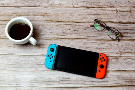 02-04-2021 Portsmouth, Hampshire, UK A Nintendo switch games console laid on a desk or table next to a coffee and glassesのeditorial素材