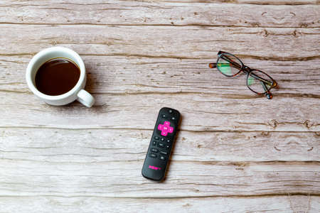 02-04-2021 Portsmouth, Hampshire, UK A Pink Now TV remote control laid on a table or desk next to glasses and a coffeeのeditorial素材