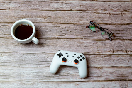 02-04-2021 Portsmouth, Hampshire, UK A google Stadia games contoller laid on a desk or table next to a coffee and glassesのeditorial素材