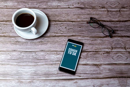 02-05-2021 Portsmouth, Hampshire, UK A mobile phone or cell phone laid on a wooden table or desk with the couch to 5K fitness app openのeditorial素材