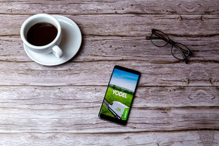 02-05-2021 Portsmouth, Hampshire, UK A mobile phone or cell phone laid on a wooden table or desk with the Yodel delivery app openのeditorial素材