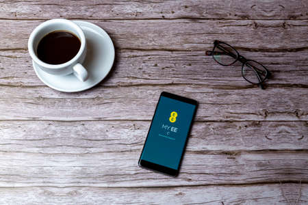 02-05-2021 Portsmouth, Hampshire, UK A mobile phone or cell phone laid on a wooden table or desk with the My EE app openのeditorial素材