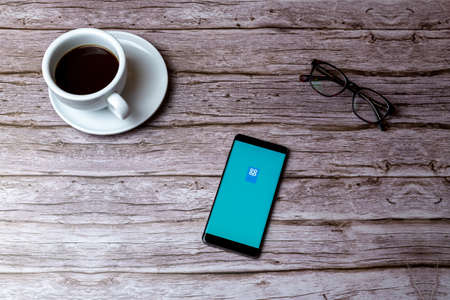 02-05-2021 Portsmouth, Hampshire, UK A mobile phone or cell phone laid on a wooden table or desk with the Co-Op app openのeditorial素材