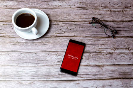 02-05-2021 Portsmouth, Hampshire, UK A mobile phone or cell phone laid on a wooden table or desk with the app openのeditorial素材