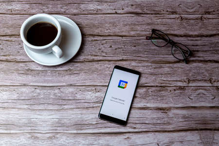 02-05-2021 Portsmouth, Hampshire, UK A mobile phone or cell phone laid on a wooden table or desk with the Google Calendar app openのeditorial素材