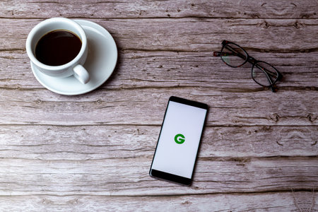 02-05-2021 Portsmouth, Hampshire, UK A mobile phone or cell phone laid on a wooden table or desk with the Groupon app openのeditorial素材