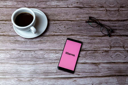 02-05-2021 Portsmouth, Hampshire, UK A mobile phone or cell phone laid on a wooden table or desk with the Klarna shopping credit app openのeditorial素材