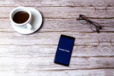 02-05-2021 Portsmouth, Hampshire, UK A mobile phone or cell phone laid on a wooden table or desk with the Football Index app openのeditorial素材