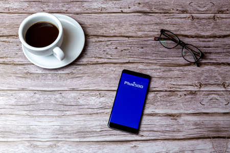 02-05-2021 Portsmouth, Hampshire, UK A mobile phone or cell phone laid on a wooden table or desk with the plus 500 trading app openのeditorial素材