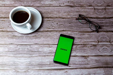 02-05-2021 Portsmouth, Hampshire, UK A mobile phone or cell phone laid on a wooden table or desk with the Shpock app openのeditorial素材