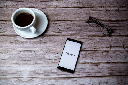 02-05-2021 Portsmouth, Hampshire, UK A mobile phone or cell phone laid on a wooden table or desk with the boohoo shopping app openのeditorial素材