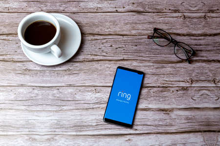 02-05-2021 Portsmouth, Hampshire, UK A mobile phone or cell phone laid on a wooden table or desk with the Ring doorbell app openのeditorial素材
