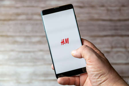 02-05-2021 Portsmouth, Hampshire, UK A Mobile phone or cell phone being held showing the H&M app open on screenのeditorial素材