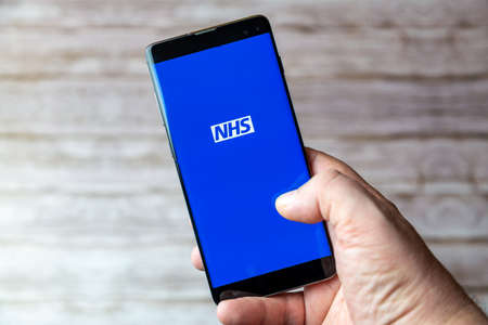 02-05-2021 Portsmouth, Hampshire, UK A Mobile phone or cell phone being held showing the NHS app open on screenのeditorial素材