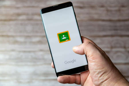 02-05-2021 Portsmouth, Hampshire, UK A Mobile phone or cell phone being held showing the Google Classroom app open on screenのeditorial素材