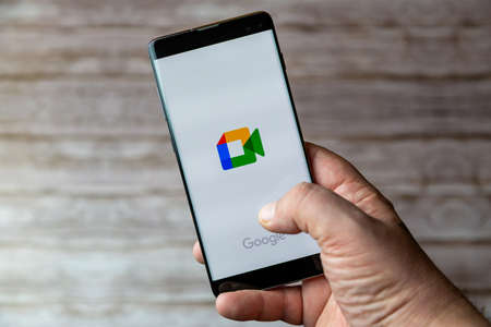 02-05-2021 Portsmouth, Hampshire, UK A Mobile phone or cell phone being held showing the Google meet app open on screenのeditorial素材