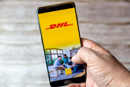 02-08-2021 Portsmouth, Hampshire, UK A mobile phone or cell phone being held in a hand with the DHL...