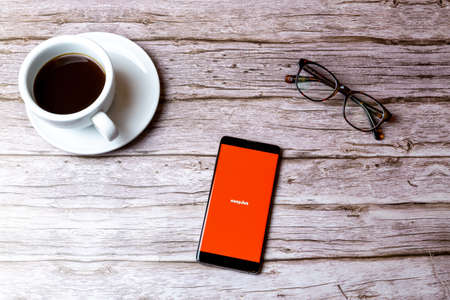02-08-2021 Portsmouth, Hampshire, UK A mobile phone or cell phone laid on a wooden table with the Easyjet app open next to a coffee and glassesのeditorial素材