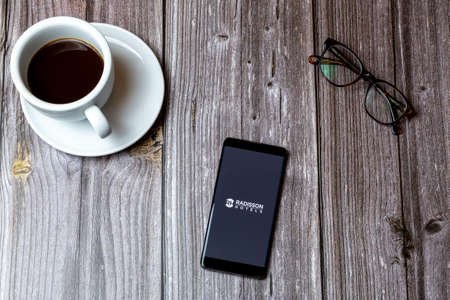 02/10/2021 Portsmouth, Hampshire, UK A mobile phone or cell phone laid on a wooden table with the Radisson Hotels app open on screen next to a coffeeのeditorial素材