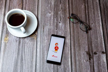 02/10/2021 Portsmouth, Hampshire, UK A mobile phone or cell phone laid on a wooden table with the Air India app open on screen next to a coffeeのeditorial素材