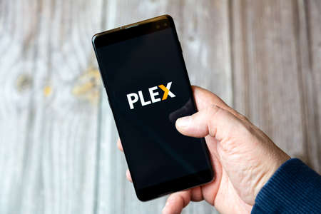 02-10-2021 Portsmouth, hampshire, UK A mobile phone or cell phone being held by a hand with the Plex app open on screenのeditorial素材