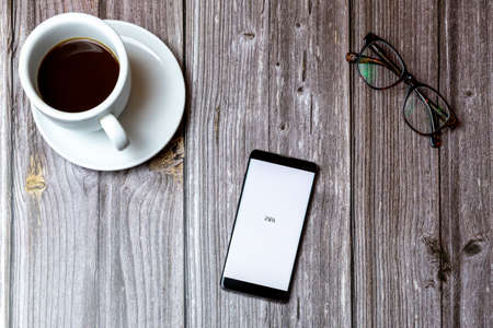 02/10/2021 Portsmouth, Hampshire, UK A mobile phone or cell phone laid on a wooden table with the Zara fashion app open on screen next to a coffeeのeditorial素材