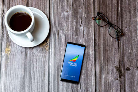 02/10/2021 Portsmouth, Hampshire, UK A mobile phone or cell phone laid on a wooden table with the Ethiopian airlines app open on screenのeditorial素材