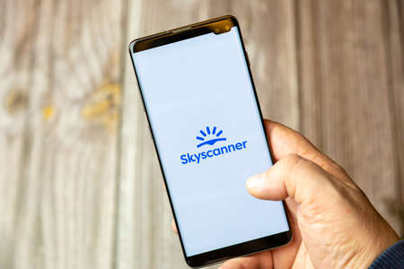 02-10-2021 Portsmouth, hampshire, UK A mobile phone or cell phone being held by a hand with the Skyscanner app open on screenのeditorial素材