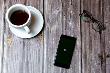 02/10/2021 Portsmouth, Hampshire, UK A mobile phone or cell phone laid on a wooden table with the wimbledon tennis app open on screen next to a coffeeのeditorial素材