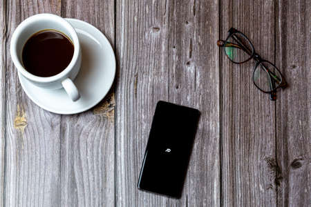 02/10/2021 Portsmouth, Hampshire, UK A mobile phone or cell phone laid on a wooden table with the JD app open on screen next to a coffeeのeditorial素材