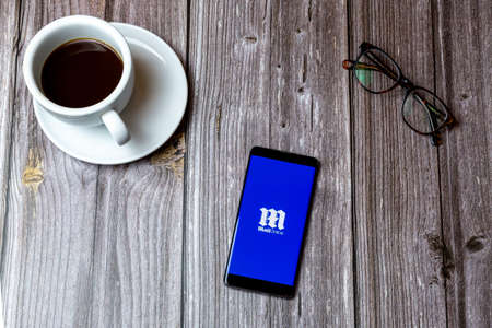 02/10/2021 Portsmouth, Hampshire, UK A mobile phone or cell phone laid on a wooden table with the daily Mail online app open on screenのeditorial素材