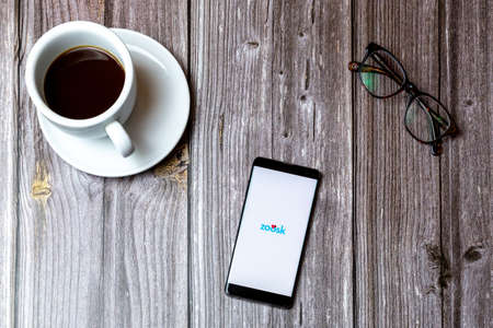 02/10/2021 Portsmouth, Hampshire, UK A mobile phone or cell phone laid on a wooden table with the Zoosk dating app open on screen next to a coffeeのeditorial素材