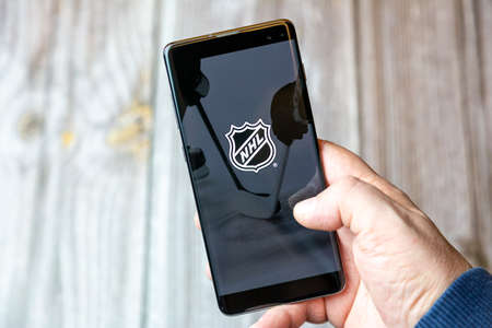 02-10-2021 Portsmouth, hampshire, UK A mobile phone or cell phone being held by a hand with the NHL Hockey app open on screenのeditorial素材