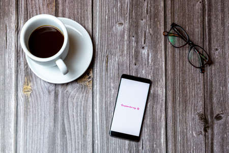 02/10/2021 Portsmouth, Hampshire, UK A mobile phone or cell phone laid on a wooden table with the superdrug app open on screen next to a coffeeのeditorial素材