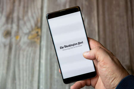 02-10-2021 Portsmouth, hampshire, UK A mobile phone or cell phone being held by a hand with the Washington Post app open on screenのeditorial素材