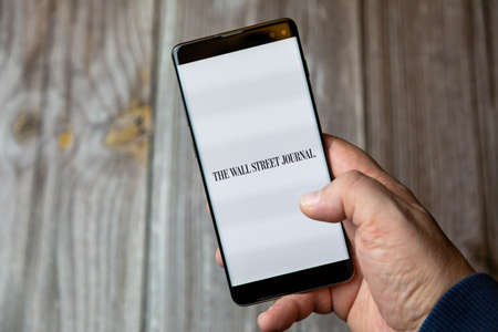02-10-2021 Portsmouth, hampshire, UK A mobile phone or cell phone being held by a hand with the Wall street journal app open on screenのeditorial素材