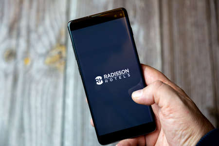 02-10-2021 Portsmouth, hampshire, UK A mobile phone or cell phone being held by a hand with the radisson Hotels app open on screenのeditorial素材