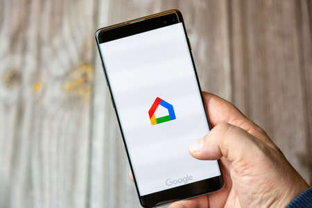 02-10-2021 Portsmouth, hampshire, UK A mobile phone or cell phone being held by a hand with the Google Home app open on screenのeditorial素材