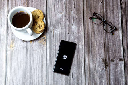 02-15-2021 Portsmouth, Hampshire, UK A mobile phone or cell phone laid on a wooden table with the 9gag app open on screenのeditorial素材