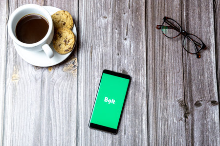 02-15-2021 Portsmouth, Hampshire, UK A mobile phone or cell phone laid on a wooden table with the Bolt Messaging app open on screenのeditorial素材