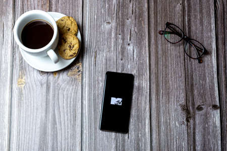 02-15-2021 Portsmouth, Hampshire, UK A mobile phone or cell phone laid on a wooden table with the MTV app open on screenのeditorial素材