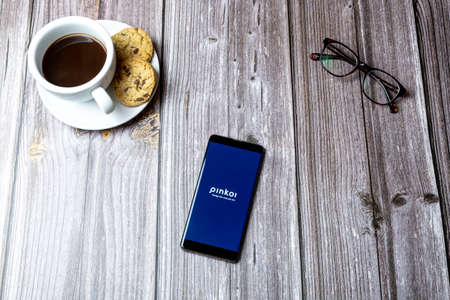 02-15-2021 Portsmouth, Hampshire, UK A mobile phone or cell phone laid on a wooden table with the Pinkoi app open on screenのeditorial素材
