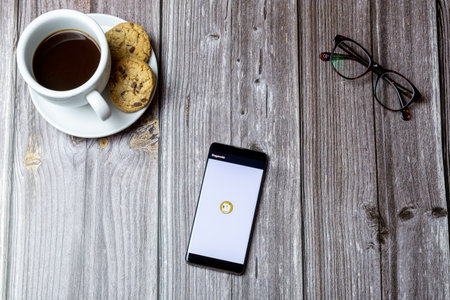 02-15-2021 Portsmouth, Hampshire, UK A mobile phone or cell phone laid on a wooden table with the Dogecoin wallet app open on screenのeditorial素材
