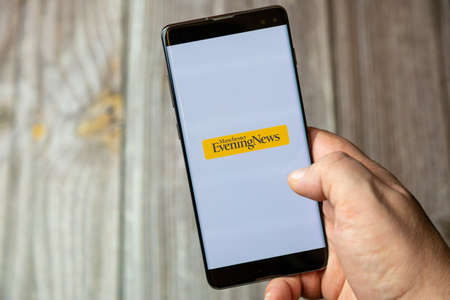 02-15-2021 Portsmouth, Hampshire, UK A mobile phone or cell phone being held in a hand with the manchester evening news app open on screenのeditorial素材
