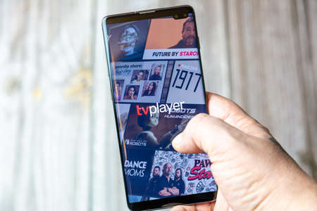 02-15-2021 Portsmouth, Hampshire, UK A mobile phone or cell phone being held in a hand with the TV player mobile app open on screenのeditorial素材