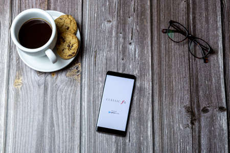 02-15-2021 Portsmouth, Hampshire, UK A mobile phone or cell phone laid on a wooden table with the Classic FM app open on screenのeditorial素材