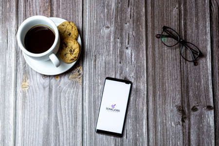 02-15-2021 Portsmouth, Hampshire, UK A mobile phone or cell phone laid on a wooden table with the Sonicjobs app open on screenのeditorial素材